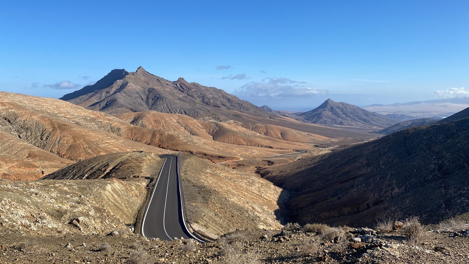 A picturesque road curves through the mountains, highlighting the breathtaking scenery and the journey ahead